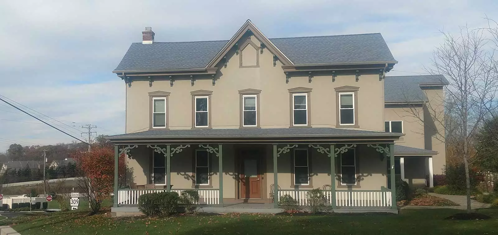 front facade of light gray farmhouse with porch in front