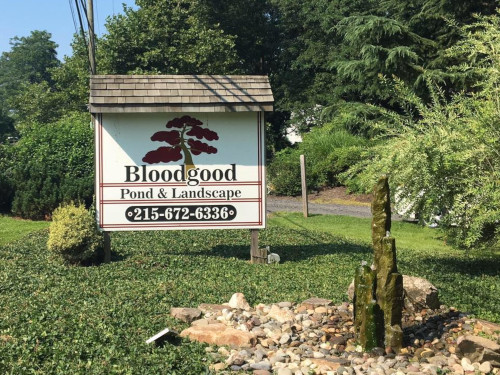 Business sign for Bloodgood Pond & Landscape with a decorative rock fountain and greenery.