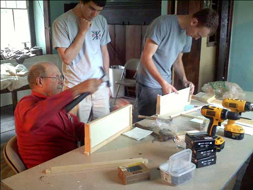 photo of pete choate with 2 young men building frames for bee hives
